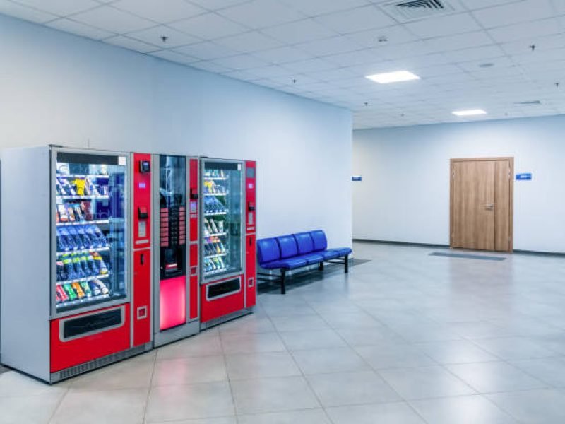 Group of red vending machines stands by the wall inside public building. No people. Unmanned store. Copy space for your text. Small business theme.