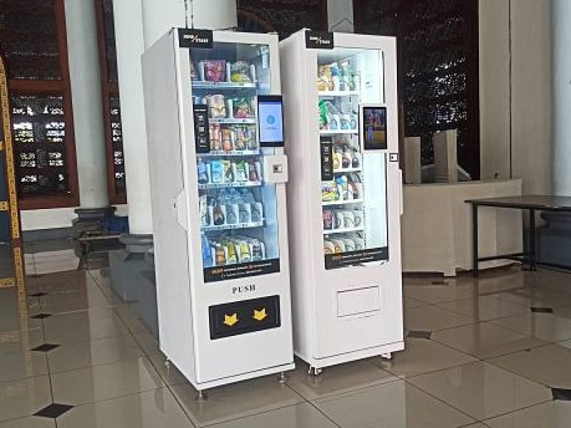 Surabaya, Indonesia – January 01, 2026: A modern beverage vending machine stands in front of Masjid Agung Al Akbar Surabaya, offering refreshing drinks to visitors and worshippers in the busy mosque area.